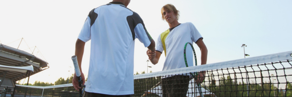 two adults shaking hands after playing a tennis game